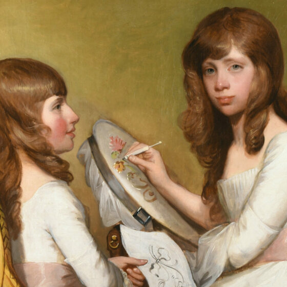 Two seemingly identical people in white dresses with a pink bow doing needlepoint.