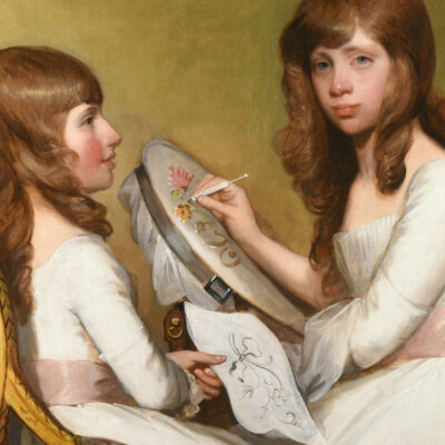 Two seemingly identical people in white dresses with a pink bow doing needlepoint.