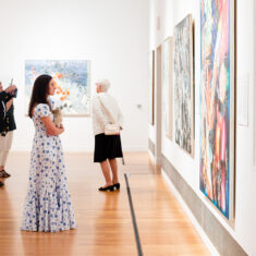 Museum visitor stands alone studying a large work of art in the gallery